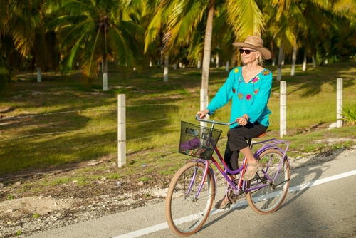 Elderly woman biking in tropical setting, embracing freedom with sharp sight