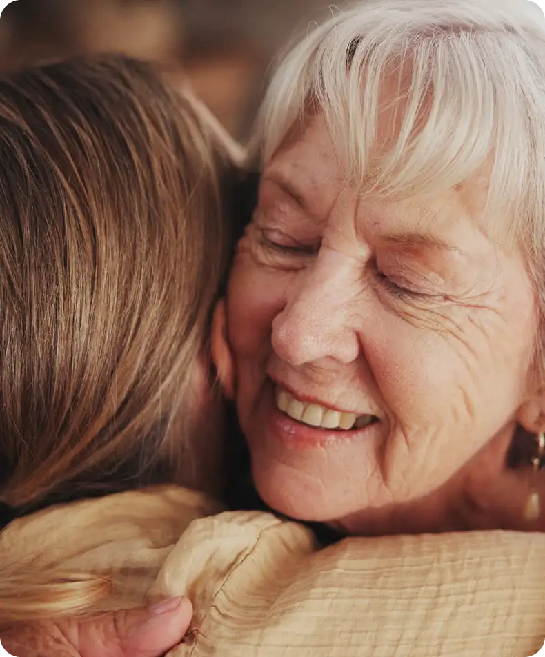 Grandmother hugging smiling granddaughter – family bonds with restored clear vision after IOLs.