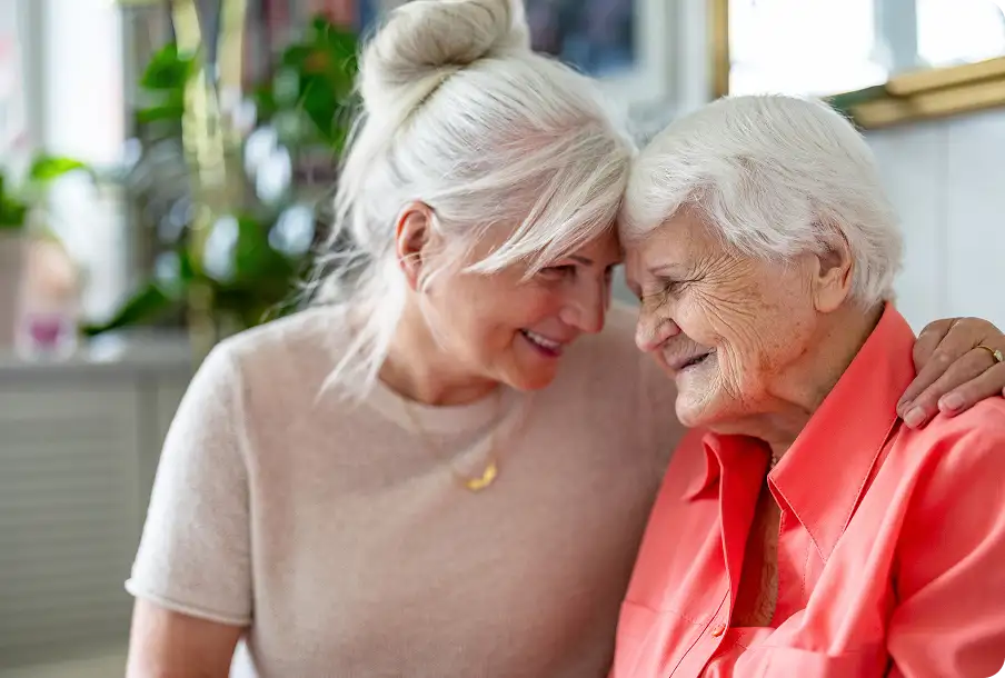 Elderly friends head-to-head smiling indoors – shared joy with premium IOLs clear vision.