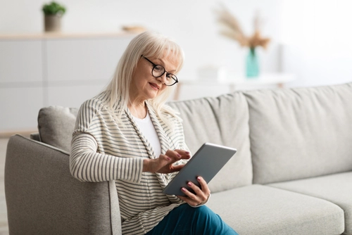 A woman with presbyopia and cataracts tries to read her tablet.