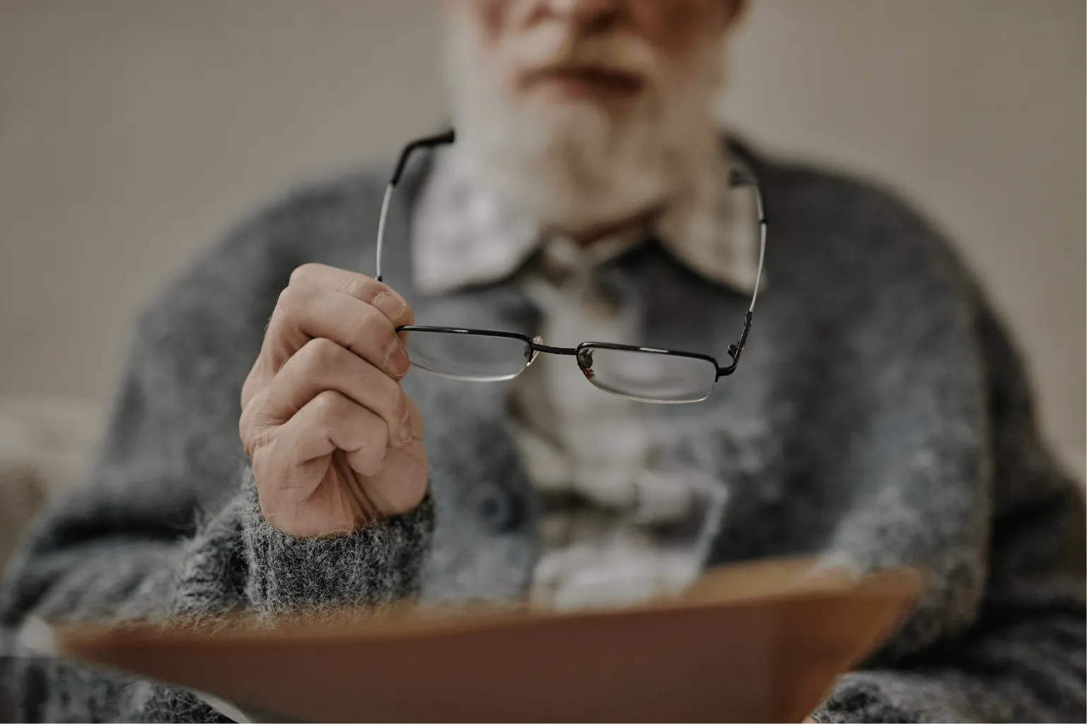 Frustrated senior patient holding glasses and questioning why new prescription doesn't work, highlighting cataract symptoms
